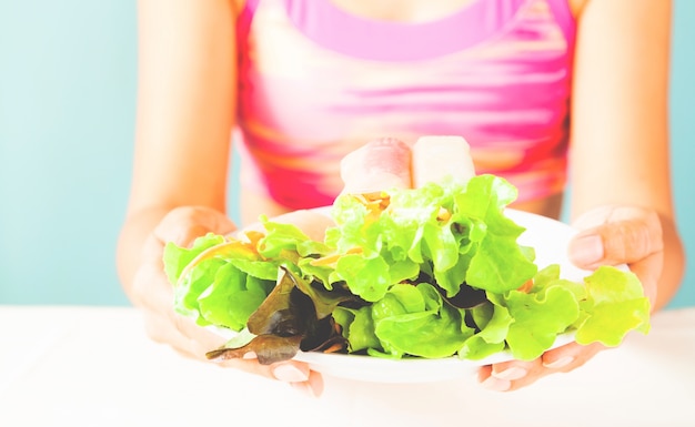 Kostenloses Foto frau im sport bh mit salat gericht nach fitness laufen workout am sommertag. fitness und gesundes lifestyle-konzept