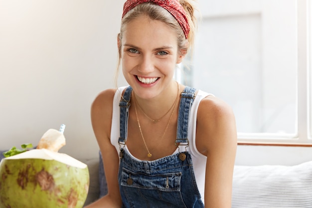 Frau im stilvollen Jeansoverall im Café