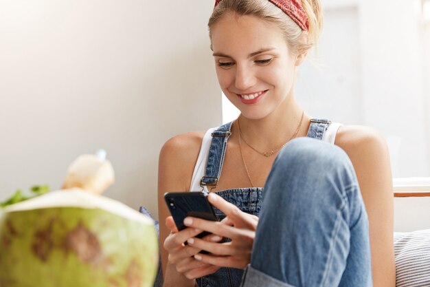 Frau im stilvollen Jeansoverall im Café