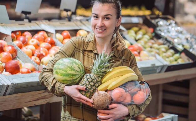 Frau im Supermarkt. Schöne junge Frau, die in einem Supermarkt einkauft und frisches Bio-Gemüse kauft