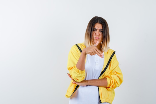 Frau im T-Shirt, Jacke, die Waffengeste zeigt und selbstbewusst aussieht, Vorderansicht.