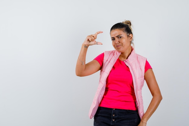 Frau im T-Shirt, Weste mit kleinem Schild und zögerlichem Blick