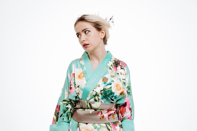 Frau im traditionellen japanischen Kimono, die beiseite schaut, verärgert und gereizt, die Augen auf Weiß rollen?