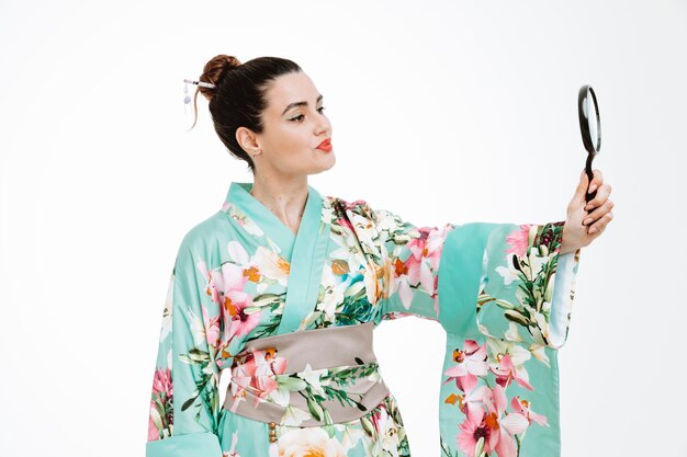 Frau im traditionellen japanischen Kimono, die Lupe hält und sie mit ernstem, selbstbewusstem Ausdruck auf Weiß betrachtet