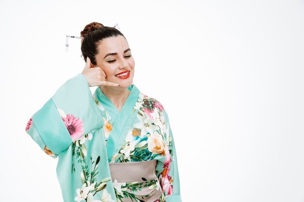 Frau im traditionellen japanischen Kimono glücklich und positiv lächelnd, rufen Sie mich an, Geste auf Weiß
