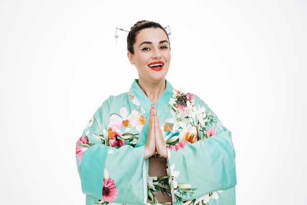 Frau im traditionellen japanischen Kimono lächelnd Händchen haltend zusammen in Grußgeste auf Weiß