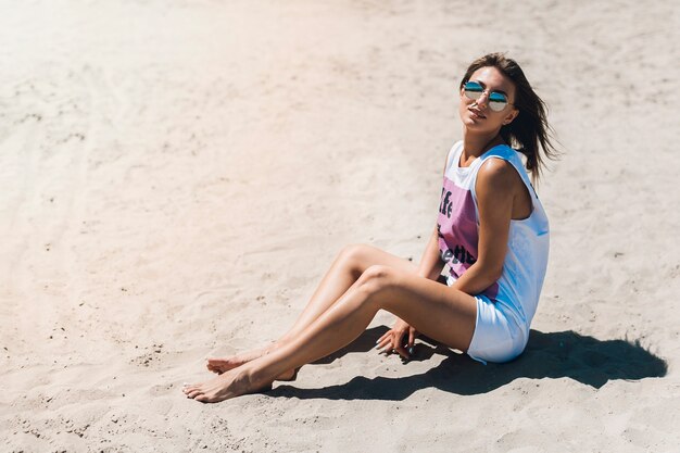 Frau im Trägershirt, das auf Strand stillsteht