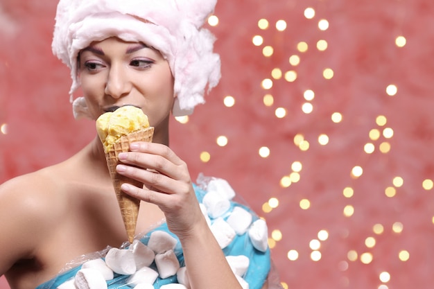 Frau im ungewöhnlichen Kleid aus Marshmallow und Perücke aus Zuckerwatte