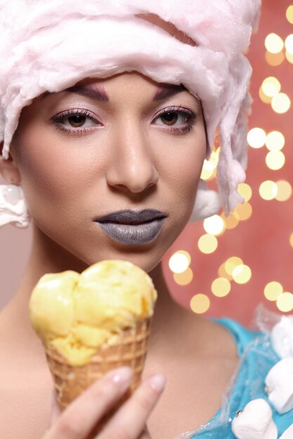 Frau im ungewöhnlichen Kleid aus Marshmallow und Perücke aus Zuckerwatte