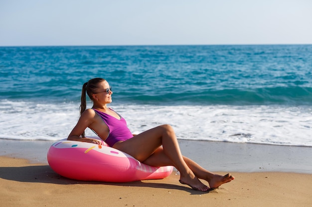 Frau im urlaub am strand entspannt in einem aufblasbaren ring am ozeanstrand auf reisen. mädchen im badeanzug an der küste in der türkei Premium Fotos