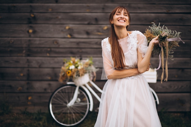 Frau im weißen Kleid mit Fahrrad durch die hölzerne Wand