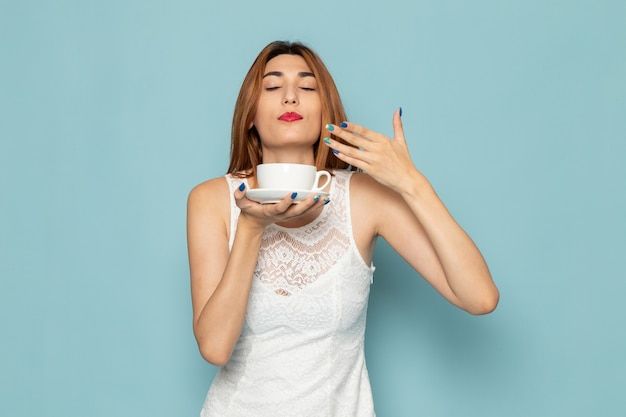 Frau im weißen Kleid riecht Tee