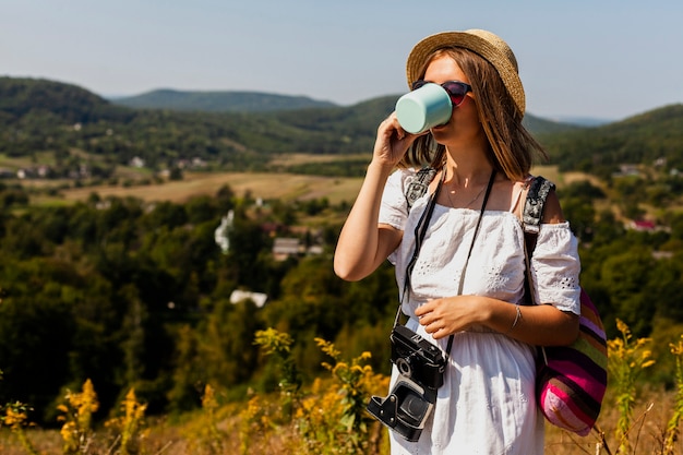 Frau im weißen Kleid trinkt aus einer Tasse