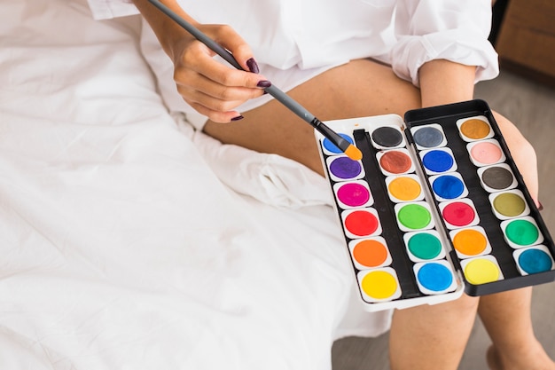 Kostenloses Foto frau im weißen sitzen mit aquarellfarben in den händen