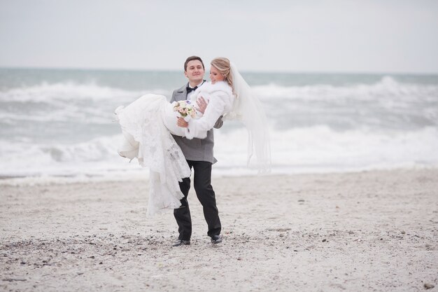 Frau in den Armen ihres Mannes am Strand