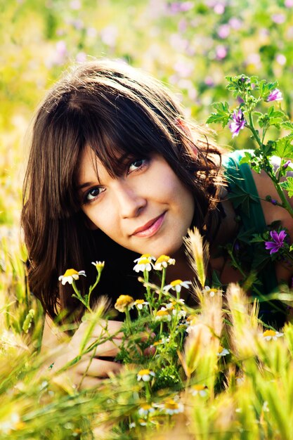 Frau in den Blumen auf der Wiese im Sonnenlicht