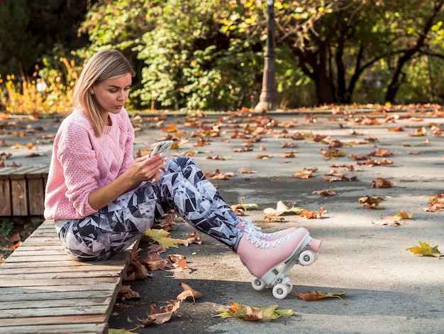 Frau in den Gamaschen und in Rollschuhen, die Smartphone mit Kopienraum halten