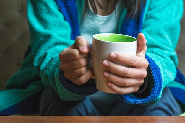 Frau in den türkisfarbenen Gewändern, die eine Tasse Tee halten