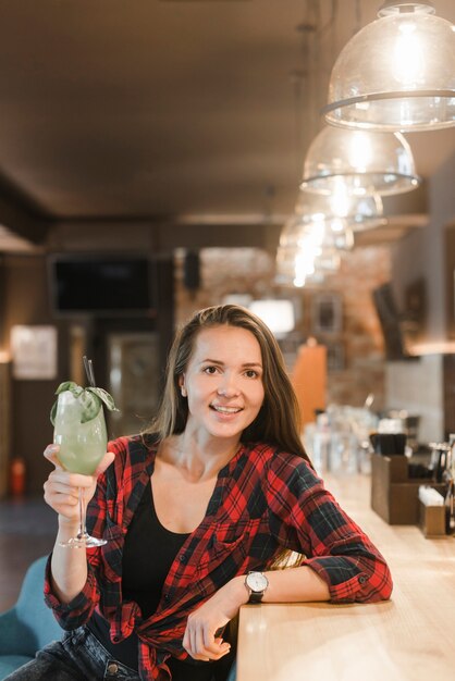 Frau in der Freizeitkleidung, die Glas des Cocktails in der Bar hält