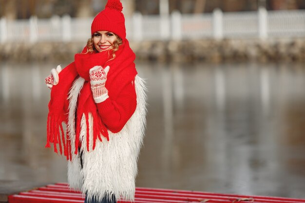 Frau in der gestrickten Wintermütze und im Schal, die Kamera mit Lächeln betrachten