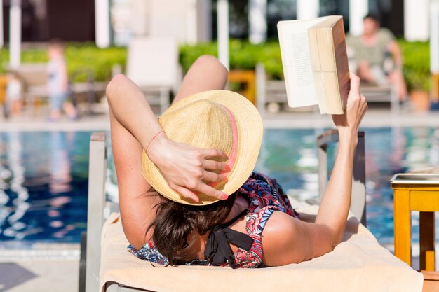 Frau in der Hängematte liegen, während ein Buch zu lesen