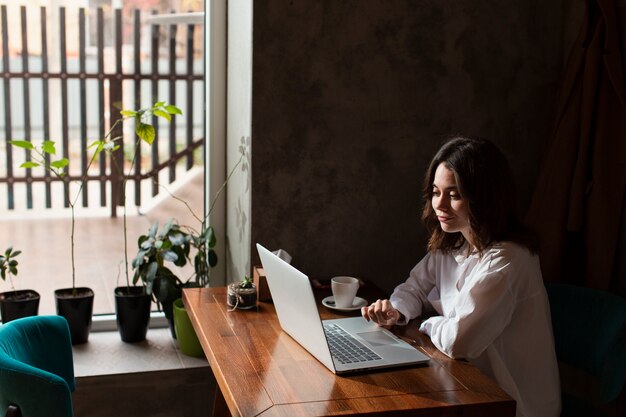 Frau in der Kaffeestube, die an Laptop arbeitet