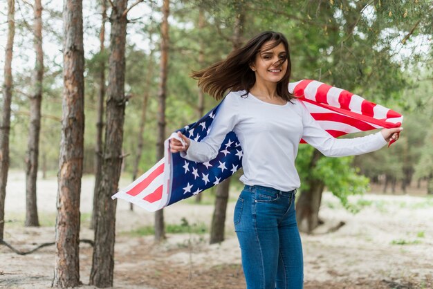 Frau in der Natur, die amerikanische Flagge hält