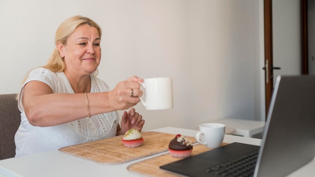 Frau in der Quarantäne, die Kaffee mit Freunden auf Laptop trinkt