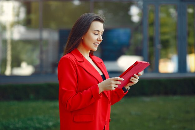 Frau in der roten Jacke unter Verwendung einer Tablette