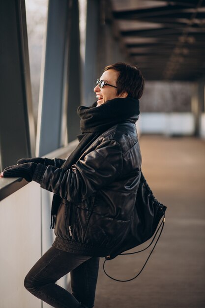 Frau in der schwarzen Jacke, die durch die Brücke geht