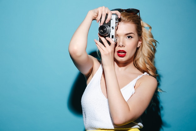 Frau in der Sommerkleidung, die Foto auf Retro-Kamera macht