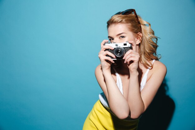 Frau in der Sommerkleidung, die Foto auf Retro-Kamera macht