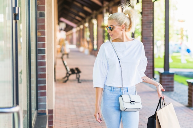 Frau in der Sonnenbrille, die Schaufenster betrachtet