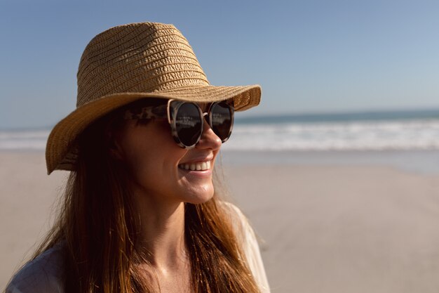 Frau in der Sonnenbrille und in Hut, die auf dem Strand sich entspannen