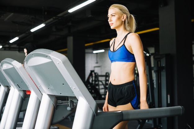 Frau in der Sportkleidung, die auf Tretmühle geht