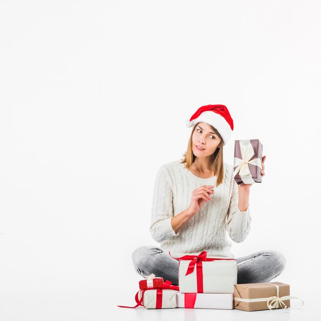 Frau in der Strickjacke, die Geschenkbox nahe Ohr hält