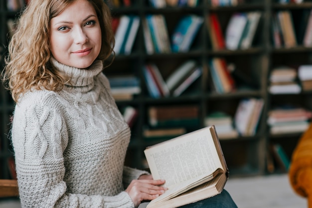 Frau in der Strickjacke in der Nähe von verschwommenen Bücherregalen