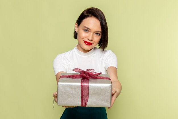 Frau in der weißen Bluse und im grünen Rock, die Geschenkbox halten