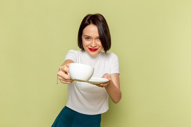Frau in der weißen Bluse und im grünen Rock, die Tasse Tee halten