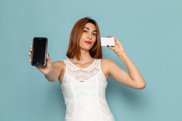 Frau in der weißen Bluse und in den blauen Jeans, die Telefon und Karte halten