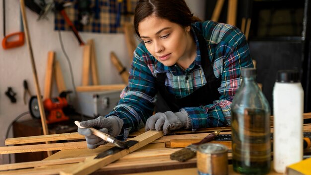 Frau in der Werkstatt, die Holzplanke malt