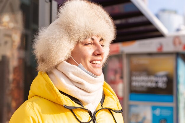 Frau in der Winterkleidung an einem kalten Tag, der an einer Bushaltestelle auf einen Bus wartet