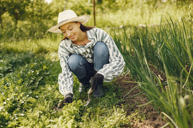 Frau in einem Hut, der in einem Garten arbeitet