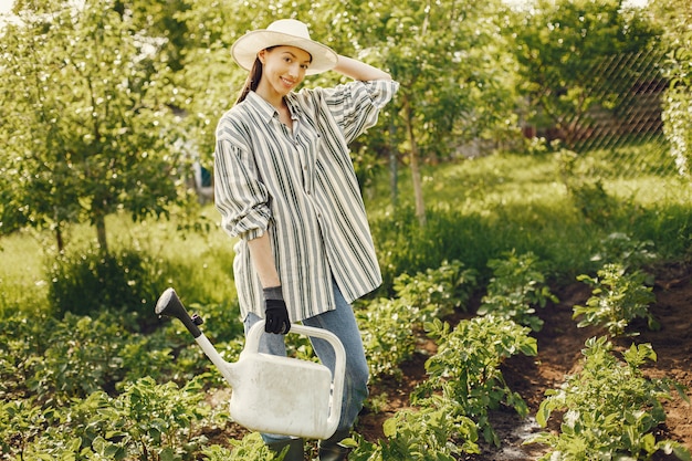 Frau in einem Hut, der Trichter hält und in einem Garten arbeitet