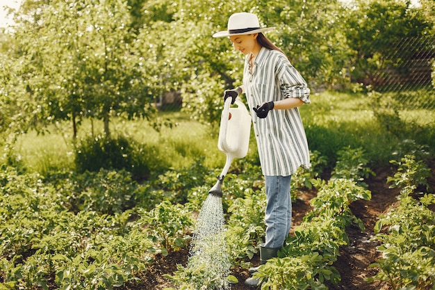 Frau in einem Hut, der Trichter hält und in einem Garten arbeitet