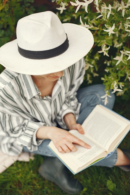 Frau in einem Hut mit einem Buch in einem Garten