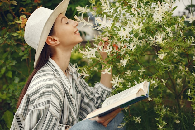 Frau in einem Hut mit einem Buch in einem Garten