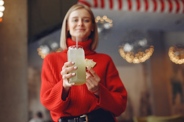 Frau in einem roten Pullover. Lady trinkt einen Cocktail.