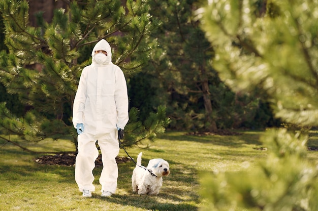 Frau in einem schutzanzug, der mit einem hund geht