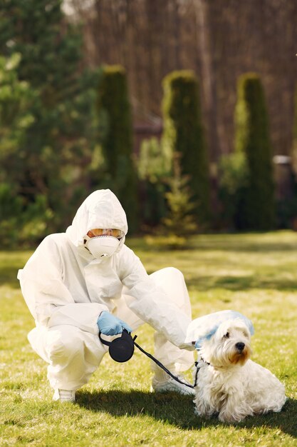 Frau in einem Schutzanzug, der mit einem Hund geht
